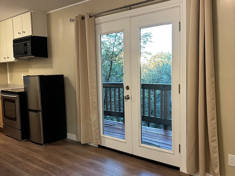 Double French Doors open up to a private deck with views of evergreen and oak trees, sunsets and Pinnacles