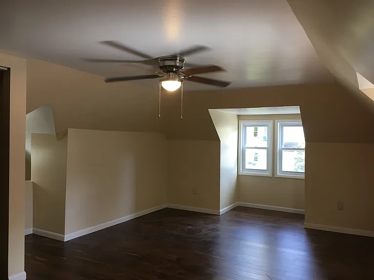 Third floor bedroom has ceiling fan and 3 windows.