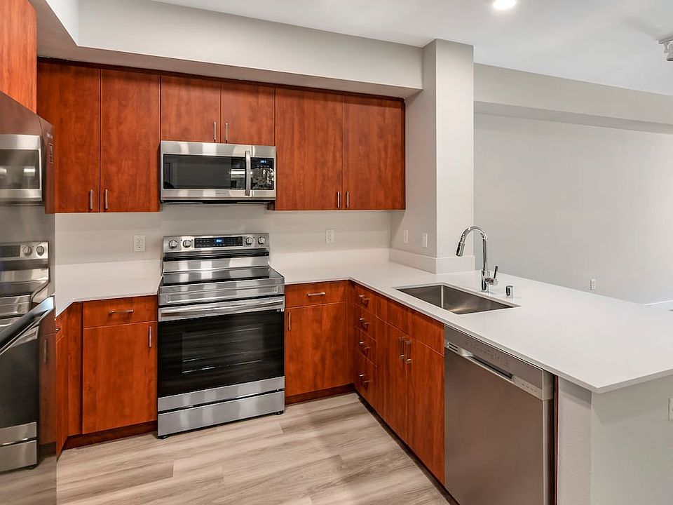 Renovated Package I kitchen with stainless steel appliances, white quartz countertops, cherry cabinetry, and hard surface flooring