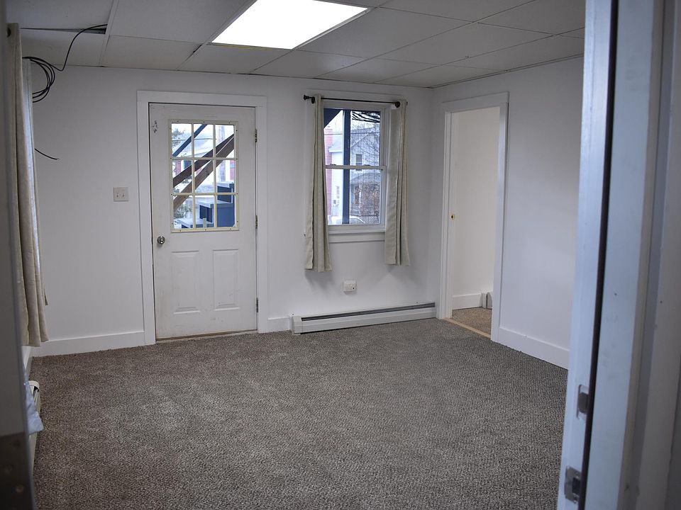 View of living/dining room. Doorway leads to bedroom. Closed front/side door leads to screened in porch