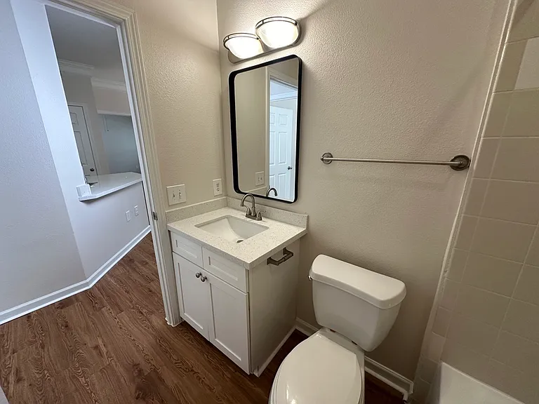 Bright and modern bathroom with sleek white cabinetry, quartz countertop, elegant lighting, and wood-style flooring. Bright and modern bathroom with sleek white cabinetry, quartz countertop, elegant lighting, and wood-style flooring.