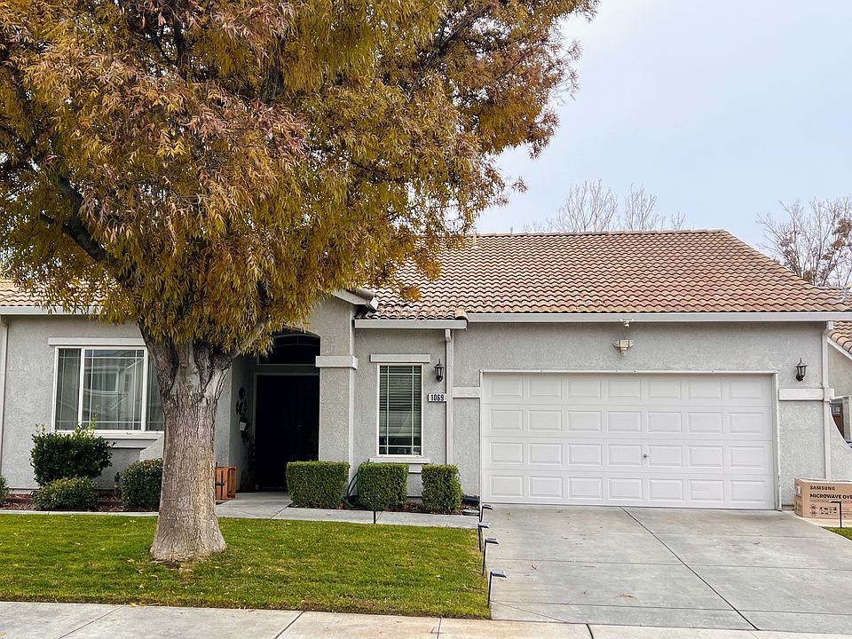 Front of the house with fully manicured landscape and drive to 2-car garage.
