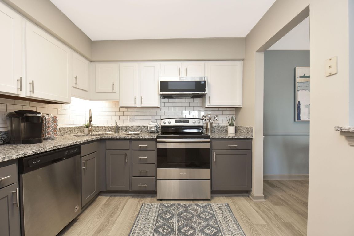 Kitchen with granite counters, stainless appliances, and two-tone modern cabinetry