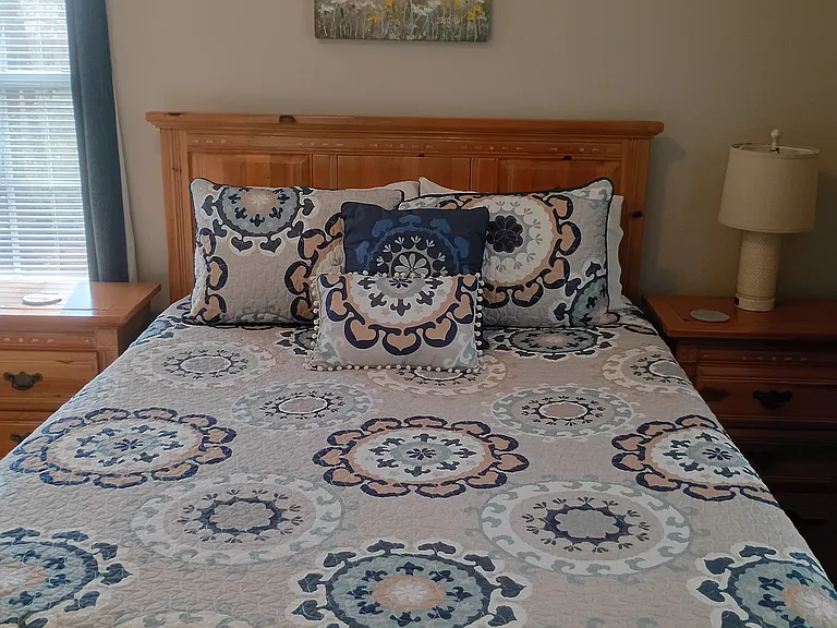 The secondary bedroom, known as the "Blue Room," features a queen-size bed, a desk and chair, and a cubby for clothing or personal items.