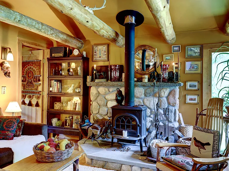 Living Area with Yotul wood stove, river rock fireplace, queen-sized sofa bed and Adirondack chair.