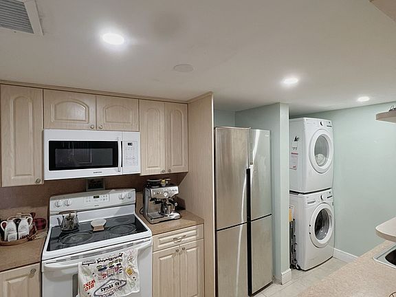 A spacious kitchen featuring a kitchen island, microwave, new refrigerator, and brand-new washer and dryer.