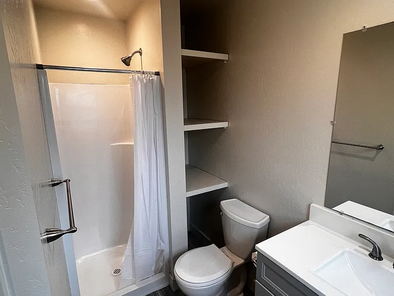 Bathroom with vanity, sink, toilet, shower and shelving