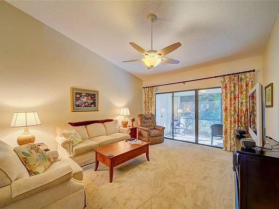 Living room with volume ceilings leading to glass sliders that open to screened porch