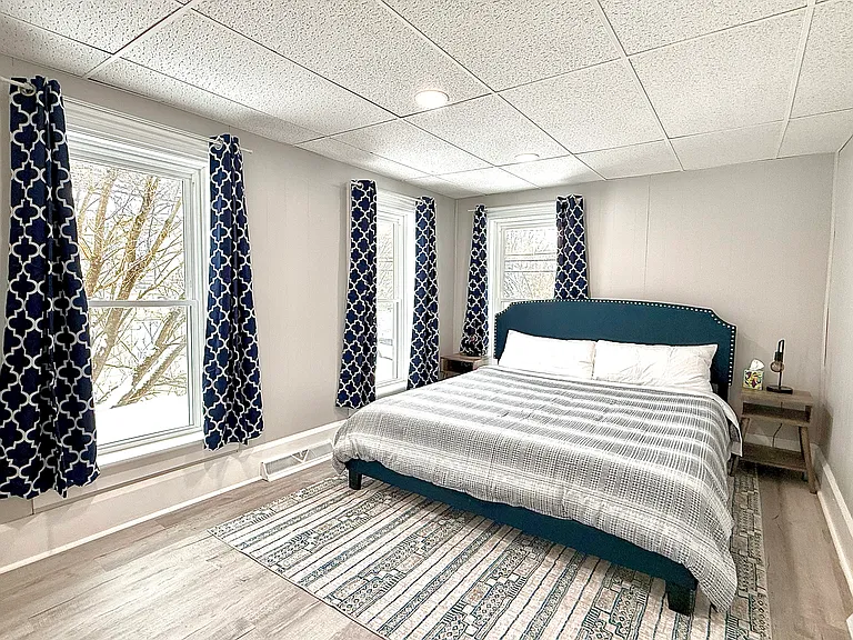 This spacious master bedroom features a king-size bed, bathed in natural light with black-out shades for a perfect balance of brightness and privacy.