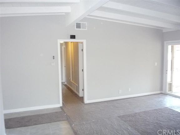 Living room with vaulted ceilings. Entry to the left and sun room to the right.