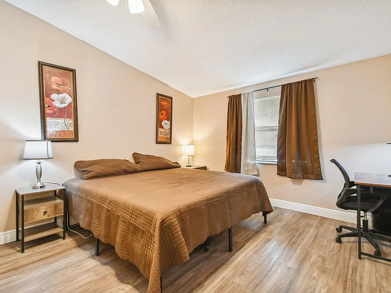 Oversized bedroom with king size bed, office desk and chair, portable AC unit controlled by remote control.