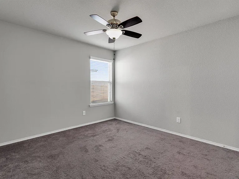 Carpeted room featuring a single window with blinds and a ceiling fan with light fixture
