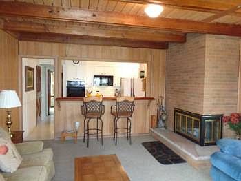 Living room features a brick wood burning fireplace and a view into the kitchen. Lots of windows for  great view of the backyard.