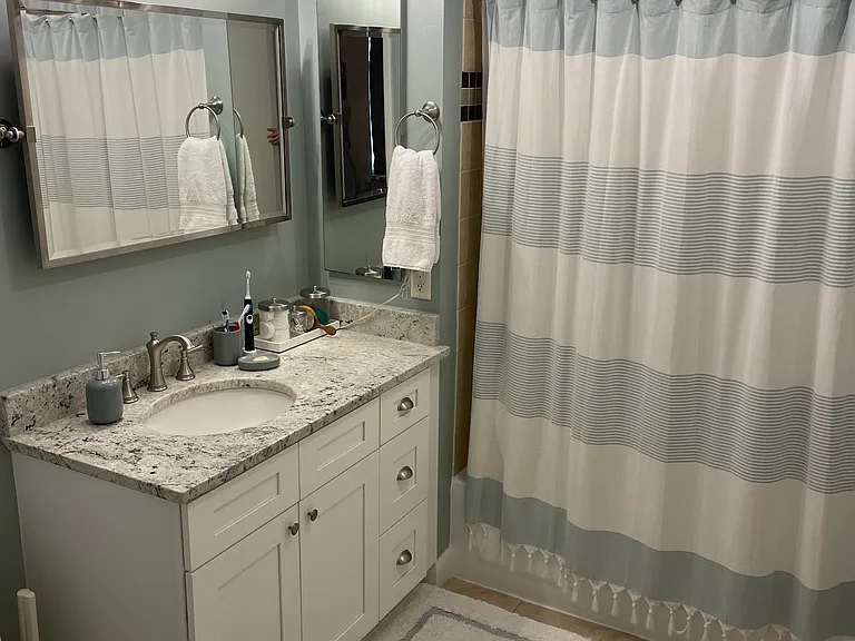 Bathroom with new granite countertop and vanity, plus a resurfaced bathtub and new light fixtures.