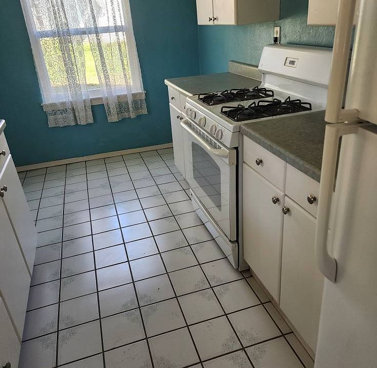 Galley kitchen with laundry connection and gas stove and refrigerator