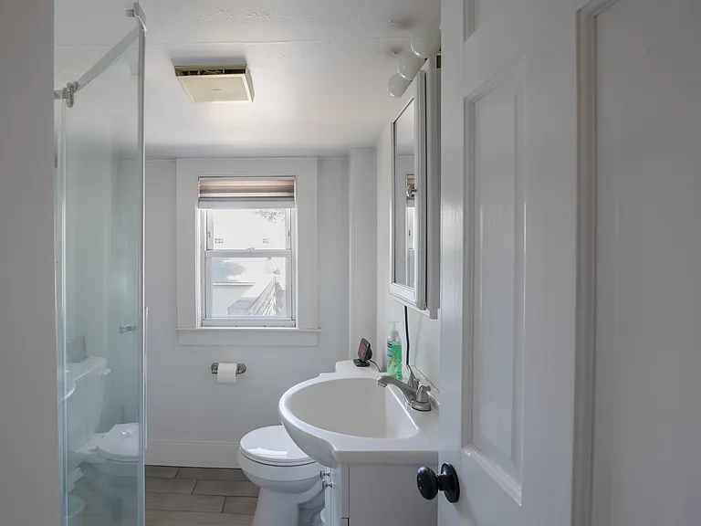 Bathroom includes a walk in shower with a washer and dryer.