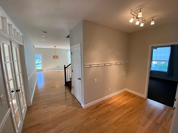 Entryway with Bedroom 5 to the right and Dining to the left through double French doors (Garage door offscreen to hard right)