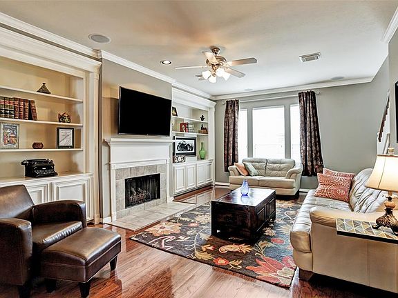 Second floor living room is bright and spacious with gleaming hardwood floors, elegant crown moulding, recessed lighting, beautiful fireplace, and oversized built-in bookcases.