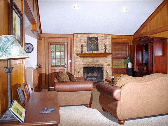 Living room lined with solid wood block paneling, and a wood burning fireplace.