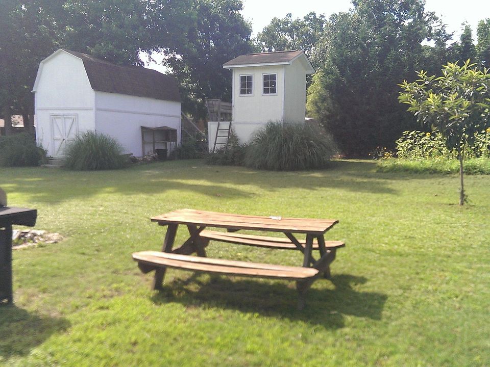 fenced in back yard with workshed and playhouse