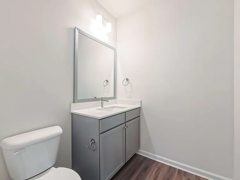 Modern bathroom with sleek gray vanity, large mirror, and elegant lighting. Bright and inviting atmosphere.
