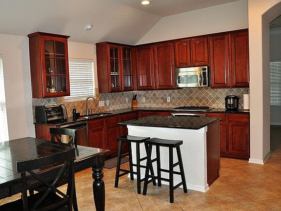 Beautiful Kitchen with Granite counters, stainless steel appliances. tumbled marble back splash and 