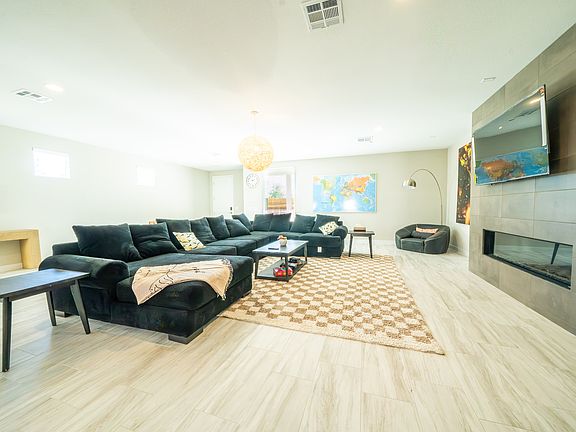 This spacious living room showcases a large sectional couch, a coffee table, and a flat-screen TV mounted on the wall, creating a comfortable and inviting atmosphere.