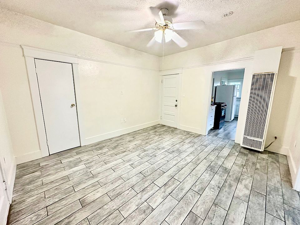 Front door and living room with wall heater and ceiling fan. Wood tile flooring.