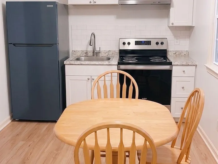 Compact eat-in kitchen with stainless range, ample white cabinetry, and a dedicated dining table for everyday meals.