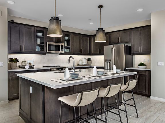 A modern and stylish kitchen with dark wood cabinets, a large island with a white countertop, and pe