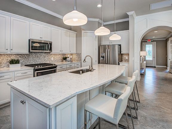 Model Representation Gourmet kitchen with curved island, stainless appliances, and decorative backs
