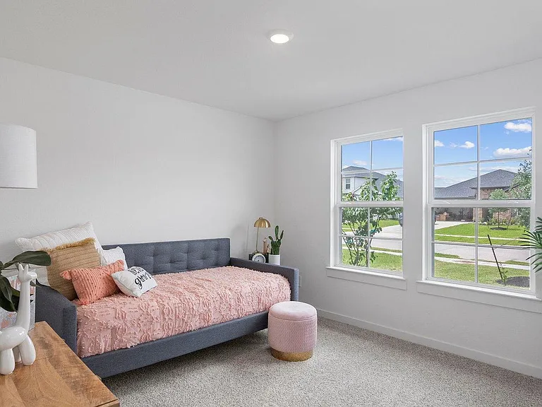 Spacious bedroom with two large windows, plush carpet, and room for a full bed plus seating or a desk.