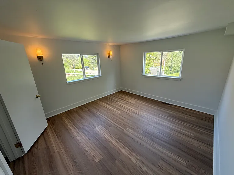 Bedroom 2. 2 large windows that have had curtain rods installed and closet with shelf and clothes rod