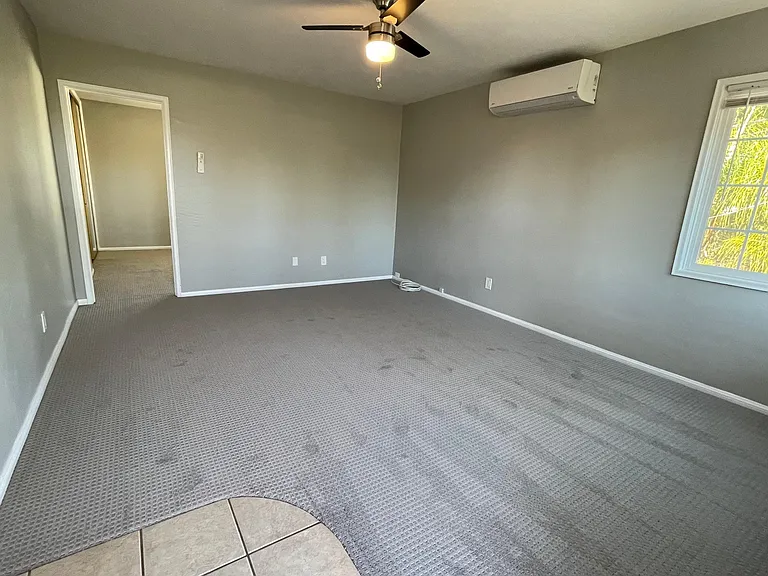 Living room with tiled entry and new carpet. AC/Heat Split and ceiling fan. This room has north and east facing windows.