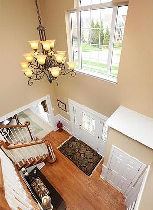 Two story entry foyer boasts beautiful wood floors, striking chandelier and arched window.