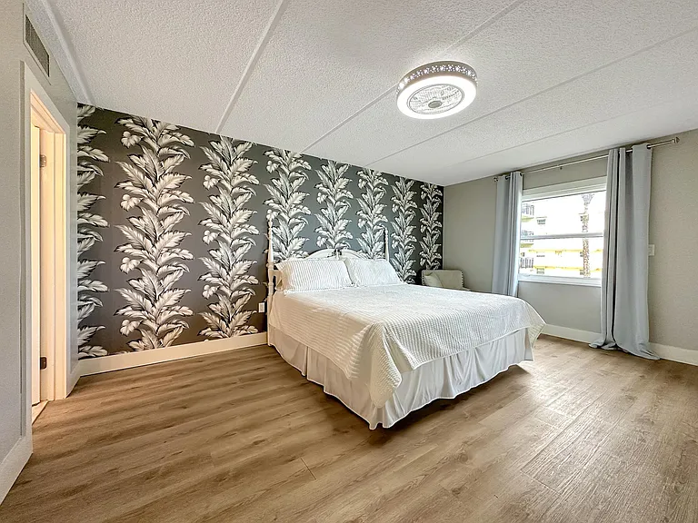 Master bedroom with doors to balcony and ocean view from them.