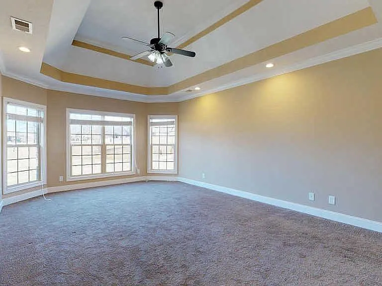 Elegant first-floor master suite featuring tray ceilings and plenty of natural light with serene backyard views.
