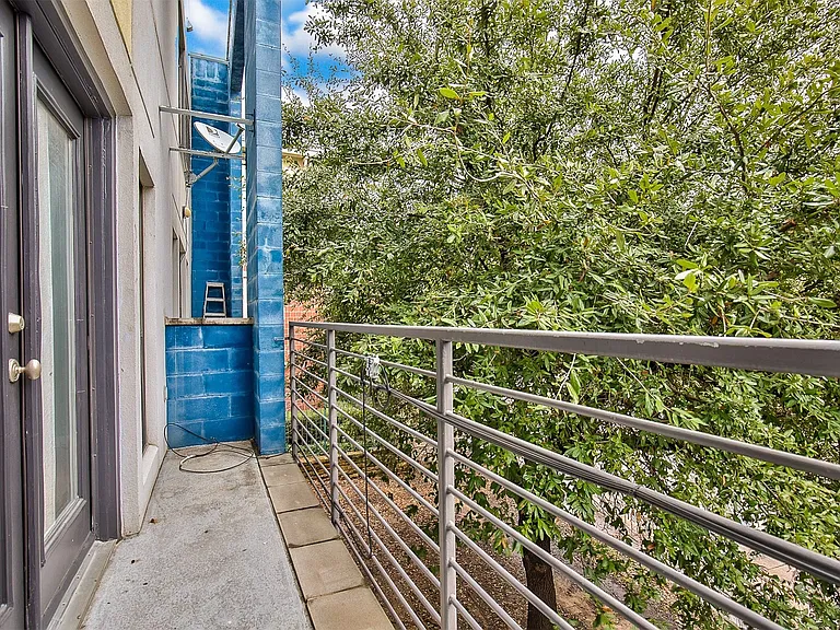 Private balcony featuring a gray metal railing, concrete flooring, and a glass-paneled door