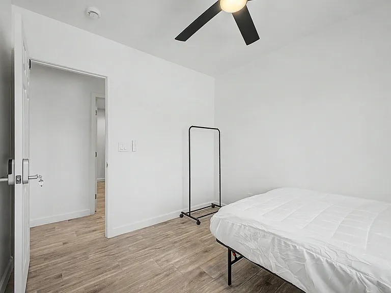 Private bedroom with wood-look flooring, ceiling fan, and convenient access to the hallway for easy daily living.