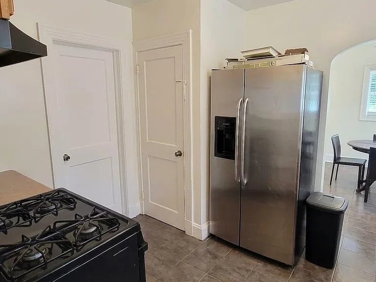 Efficient kitchen with gas range, side-by-side refrigerator, ample cabinetry, and an adjacent dining nook with window.