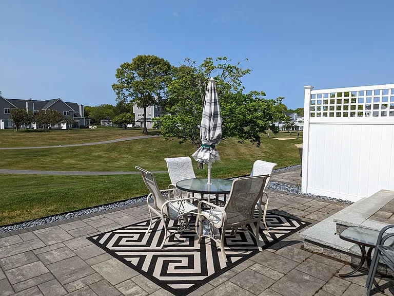 private patio furnished with carpet, table, comfortable chairs, umbrella