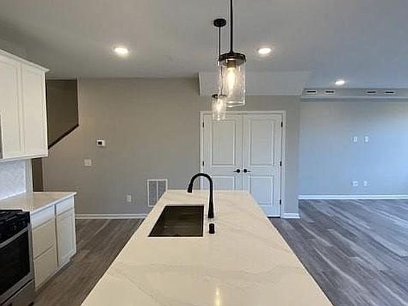 Tasteful white cabinetry and tile backsplash. Neutral colors and vinyl plank flooring throughout main level. Actual home pictured here.