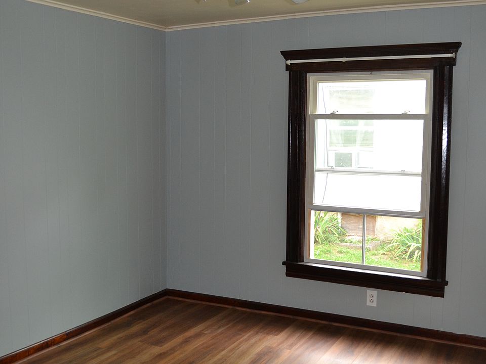 Bright and inviting dining room with a large window allowing in ample natural light. Elegant dark wood trim contrasts beautifully with the fresh wall color and durable flooring.