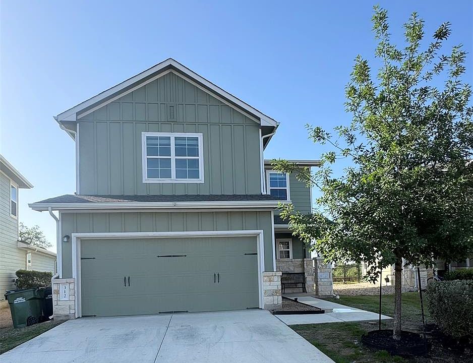 Craftsman-style house with board and batten siding, an attached garage, stone siding, and concrete driveway