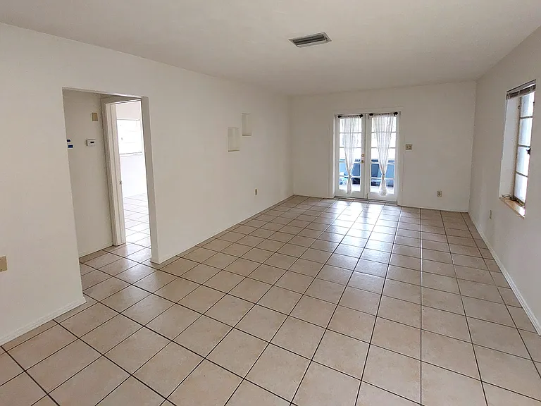 Living/Dining room with French doors leading to screened-in front porch.