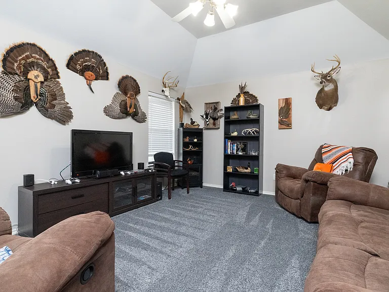 Cozy media room with plush recliners, TV, bookshelf, and rustic decor. A laid-back space to watch movies, play games, or unwind with your group.