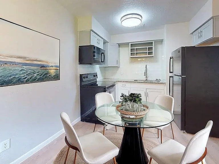 Chic apartment kitchen with modern appliances, cozy dining area, and elegant wall art.