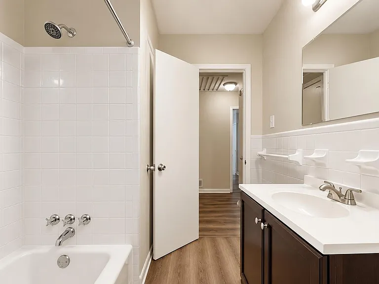 Full bath with tiled tub/shower, wide vanity counter, and large mirror for easy daily routines and storage.