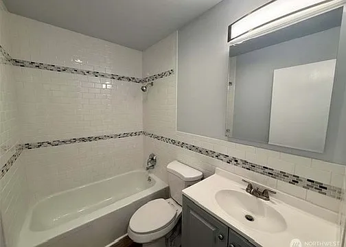 updated bathroom with new tiled shower, new vanity, toilet and new flooring