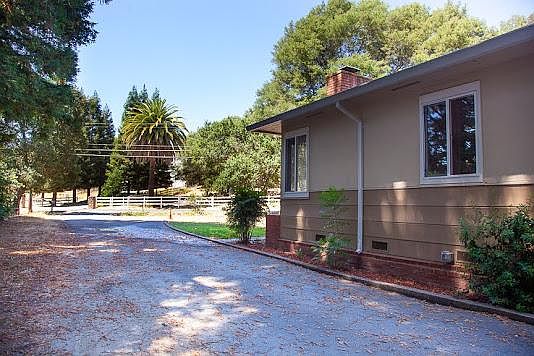 View of driveway facing Third Ave. Large redwood trees line the left side of the driveway.